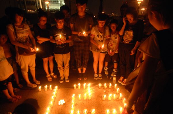 Local residents hold candles to mourn for the victims of a train crash in Wenzhou, east China's Zhejiang Province, July 26, 2011. At least 39 people died and 192 others were injured in the accident that occurred on July 23, 2011 on a bridge near Wenzhou when bullet train D301 rear-ended D3115. (Xinhua/Huang Zongzhi)