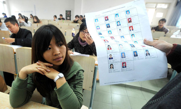 An exam supervisor checks candidates' information before the 2012 national civil service exam starts in Heifei, capital of East China's Anhui province, Nov 27, 2011. The exam offers about 18,000 posts in China's public service system. Around 970,000 people take part in the exam. [Photo/Xinhua]