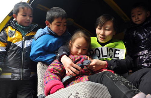 Xu Zhongmei, an officer at the Shuijiahu police station in Changfeng county, Anhui province, teaches students from a local kindergarten how to use the seat belt in a school bus on Monday. [Liu Junxi /