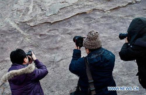 Photographers shoot fossilized footprints at a geological park in Yanqing County, 