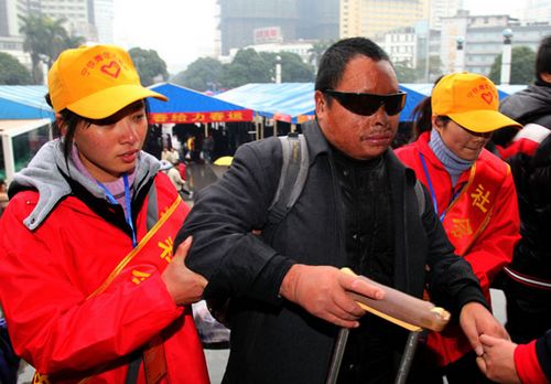 Two volunteers help a blind man enter the waiting hall of Nanning Railway Station in the Guangxi Zhuang autonomous region on Sunday. (Photo: China Daily)