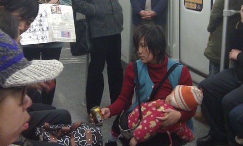 A woman with an infant begs for money on metro Line 1. [Photo: Chen Xiaoru/GT]