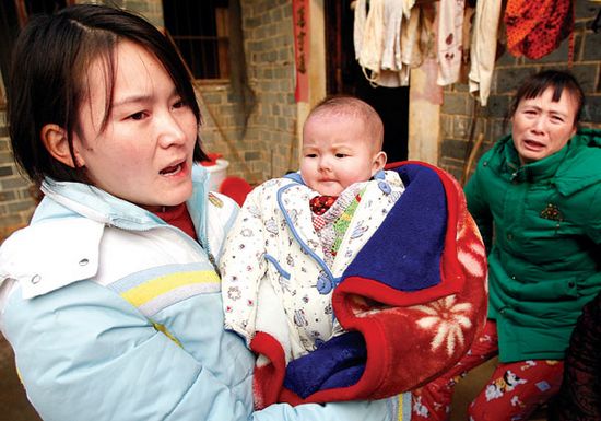 The mother of twins, Cao Haijuan, holds the surviving daughter in Duchang county, Jiangxi province, on Thursday. (Photo: China Daily)