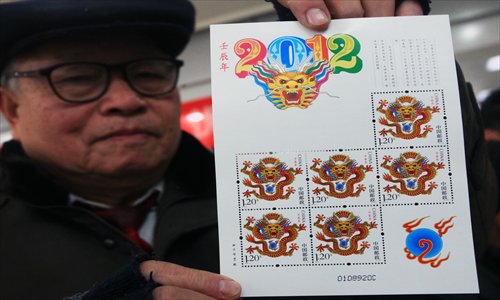 A man displaying the fierce 2012 dragon stamps Photo: CFP 