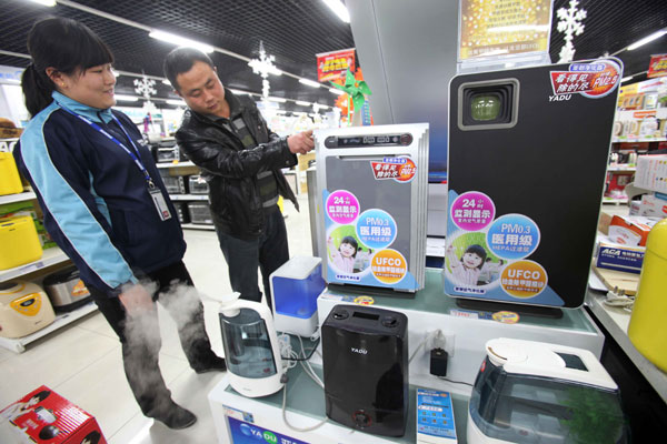 A customer discusses air purifiers with a saleswoman at a chain store of domestic retailer Suning Appliance Co Ltd in Beijing late last month. [Photo/China Daily]