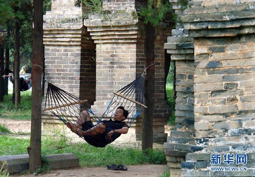 A staff member of Shaolin Temple is sleeping in a hammock hanging between two trees.