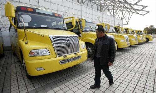 A man looks at a row of new school buses purchased by Chongming officials, parked at Shanghai Chongming High School Tuesday. Seventeen school buses will be used to transport kids to and from school this month after the winter break. Photo: Lu Yun/GT