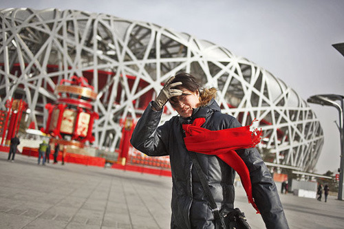 A tourist braves strong wind in Beijing on Monday. A large part of the country will experience colder than usual weather in the coming days, meteorologists said. [Photo: China Daily]