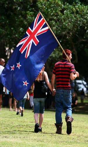 A couple wave a New Zealand flag while enjoying themselves on Waitangi Day. [Photo: CFP]