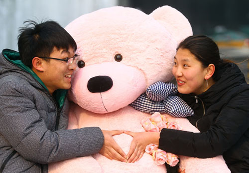 Kang Zhiming and his girlfriend Meng Xue have fun with a giant toy bear at Oriental Plaza in Beijing's Wangfujing Street on Monday. Zou Hong / China Daily 