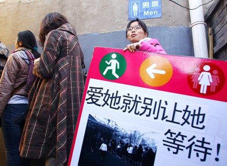 Women line up outside a men's toilet in Beijing on Sunday in a campaign that calls for more facilities for women. If you love her, don't let her wait in line, reads the sign. [Zou Hong / China Daily]