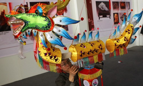 Yang Yurong, a national inheritor of intangible cultural heritage, shows his handmade dragon shaped lantern during a recent exhibition. Photo by Zou Hong / China Daily