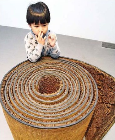 A girl is attracted by Sui Jianguo's sculpture Kill on display at Beijing's 798 art zone. [Jiang Dong / China Daily]