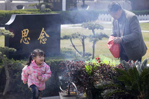 A man burns incense to honor relatives at a cemetery in Shanghai on Sunday. Yong Kai / for China Daily 