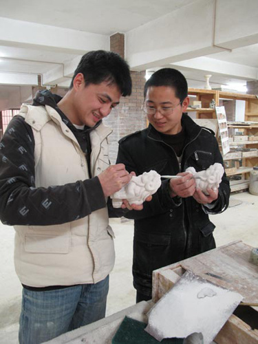 Gao Ling (left) discusses his new work with classmate Chen Wei. Gao, who has a small workshop in the city, is confident about his creativity. Yang Wanli / China Daily