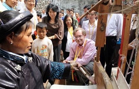 World Bank President Robert Zoellick looks into conditions in Xianahui county of Qianxinan autonomous prefecture in Guizhou province in this file photo taken last September. Here, he watches a villager demonstrating spinning techniques. [Photo / China Daily]