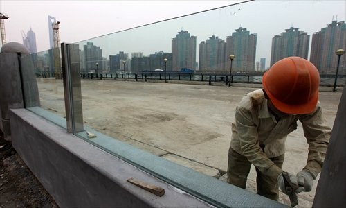 A worker installs panes of glass on the flood wall at the south Bund Sunday. The 109-meter wall has already passed safety inspections. Photo: Lu Yun/GT 