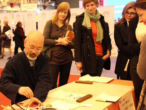 A Chinese calligrapher writes for visitors to the London Book Fair 2012 on Monday. [Photo: Mei Jia / China Daily]