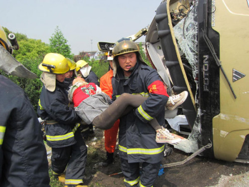 Fire fighters carry an injured passenger after a collision between a truck and bus killed 13 people and left many injured in the Changshu section on an expressway in E China's Jiangsu Province, April 22, 2012.[Photo/Xinhua]