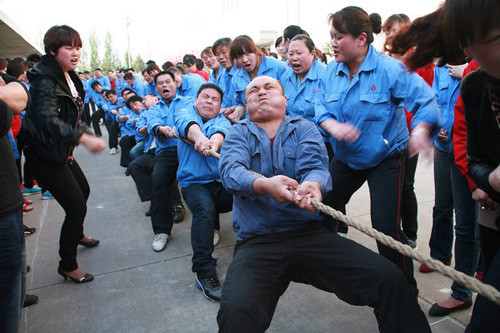 Migrant workers of Jifa Group in Qingdao, Shandong Province, have a tug-of-war recently. Liang Xiaopeng / for China Daily