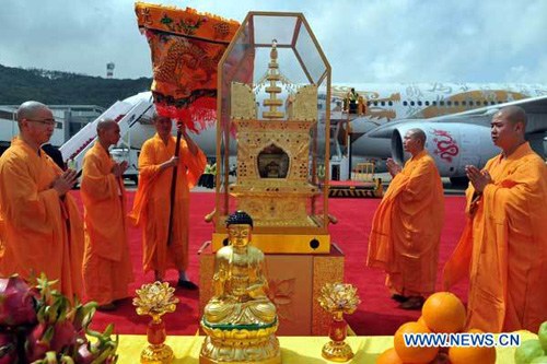 Monks perform a welcoming ceremony as a glass box containing a rare piece of parietal-bone relic of Sakyamuni, the founder of Buddhism, arrives at the airport in Macao, South China, April 30, 2012. The parietal-bone relic is to open for public worship for