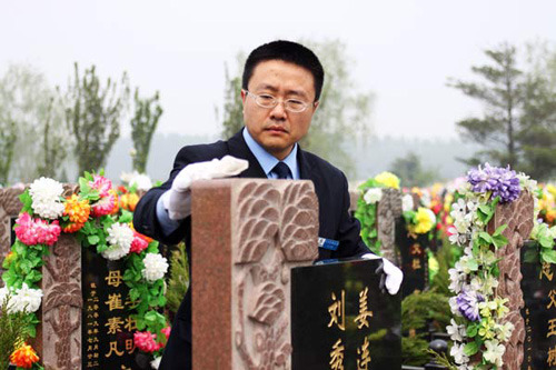 On April 23, Jiang Xiao, a worker at Daxing Funeral Parlor, cleans a tombstone in a graveyard in Beijings Daxing District. [Photo: Liu Zhe / China Daily]