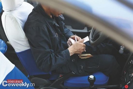 A taxi driver is counting the money for contract fees on May 2, 2012. In Beijing, taxi drivers have great financial pressure.