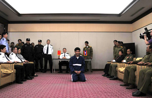 Naw Kham (C), head of an armed drug gang, kneels during a transferring at Laos' Vientiane Wattay International airport, May 10, 2012. Naw Kham, a drug lord suspected of masterminding the murder of 13 Chinese sailors on the Mekong River last year was transferred to Chinese police here on Thursday. [Photo/Xinhua] 