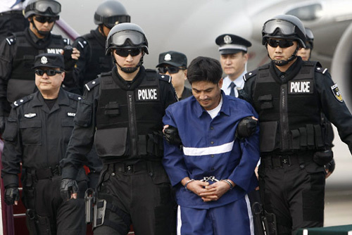 Naw Kham (2nd R, front), a drug lord suspected of masterminding the murder of 13 Chinese sailors on the Mekong River last year, is escorted to get off the plane in Beijing, capital of China, May 10, 2012.[Photo/Xinhua]