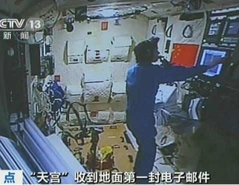 A TV screen shot shows an astronaut onboard the Tiangong-1 space module lab receiving an e-mail fron Earth, June 19, 2012. [Photo/CCTV]