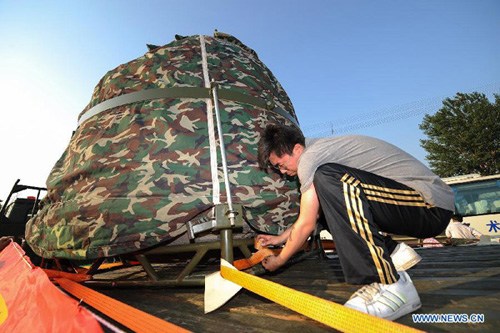  A staff fixes the return capsule of the Shenzhou-9 manned spacecraft on a truck after the capsule arrived in Changping, a suburb of Beijing, capital of China, June 30, 2012.