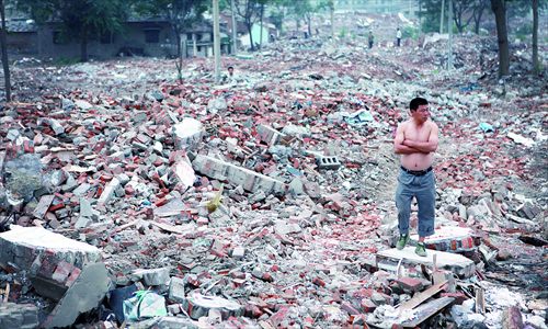 A resident stands on the ruins of the houses that were allegedly forcibly demolished Monday. 