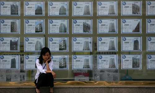 A woman sits in front of a Beijing real estate agency. A property entrepreneur is recruiting people to join his co-operative housing project to promote affordable housing in Beijing.