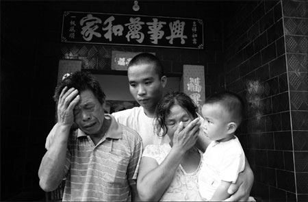 Li Guoqi comforts his parents in Pingdingshan, Henan province, on Wednesday. Li and his fellow fishermen were rescued on July 17 after being held hostage by Somali pirates for 19 months. [Photo: China News Service]