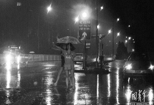 Two people try to hail a cab in the rainstorm in Beijing, July 22, 2012.