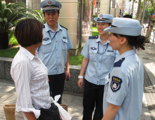 Ding Tao(second from the left), a chengguan who has a master's degree, works with his colleagues to persuade a peddler near Shanghai's bustling Nanjing Road to move on.