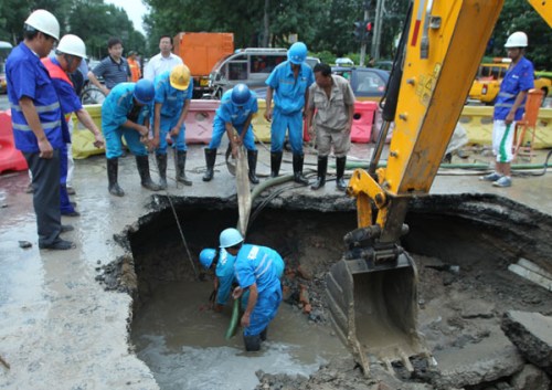 Workers repair a section of collapsed road in Chaoyang district in Beijing on Wednesday.