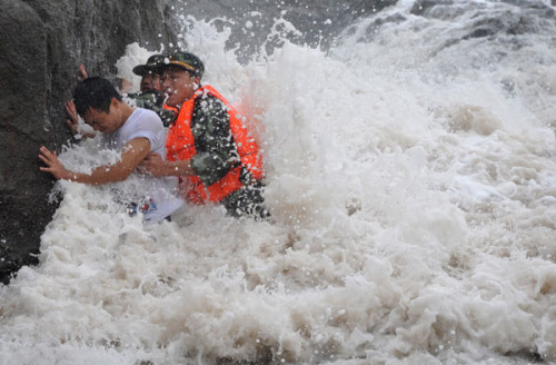 Border guards in Taizhou, Zhejiang province, help a tourist who got into difficulty near the city's beach as winds whipped up waves. Typhoon Saola was on target to hit the province on Friday.