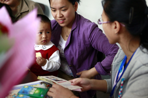 A volunteer gives family planning booklets and condoms to a migrant woman at an event in May in Wuxi, Jiangsu province.