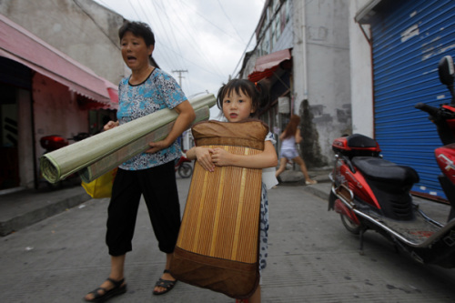 A girl and her grandmother move to a school in Jinwei, a village in the suburb of Shanghai, to fi nd shelter from Typhoon Haikui on Tuesday. 