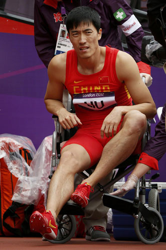 China's Liu Xiang is assisted onto a wheelchair after suffering an injury during his men's 110m hurdles round 1 heat during the London 2012 Olympic Games at the Olympic Stadium August 7, 2012.