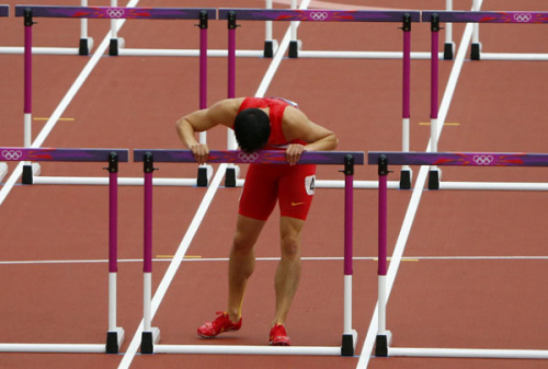 Liu Xiang kisses the last hurdle in his lane after crashing into the first hurdle and failing to finish his men's 110m hurdles round 1 heat at the London 2012 Olympic Games at the Olympic Stadium August 7, 2012.