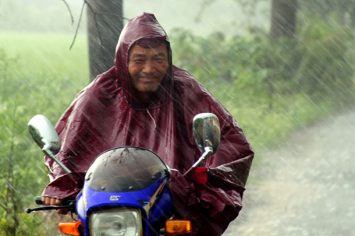 A man rides an electric motor in the torrential rain in Hanshan County, Maanshan City,east China's Anhui Province, Aug. 8, 2012. Anhui Provincial Meteorologic Bureau has issued orange pre-alert signal as typhoon Haikui is excepted to land in the south of 