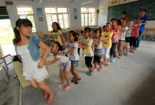 Students from Guangxi University of Science and Technology play with pupils in Tantou township, Liuzhou city, Guangxi Zhuang autonomous region, in July. English, dancing, painting and calligraphy classes were held for the pupils during summer vacation. 