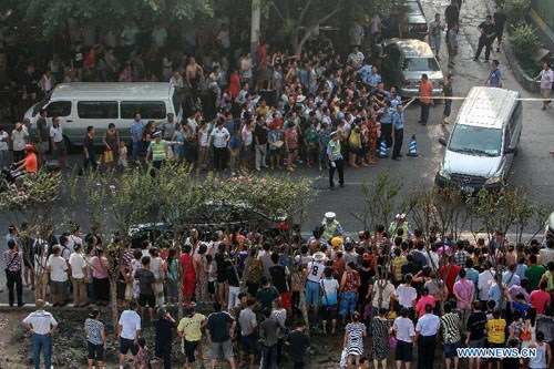 People gather as police convey the body of Zhou Kehua, a serial killer who was shot dead by police in southwest China's Chongqing on Aug. 14, 2012. Zhou Kehua killed nine and wounded several others in armed robberies since 2004. (Xinhua/Chen Cheng)