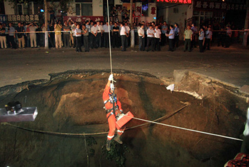 A firefighter prepares to search for trapped people in a 10-meter-deep pit caused by a road cave-in in Northeast China's Harbin city. [Photo/Xinhua]