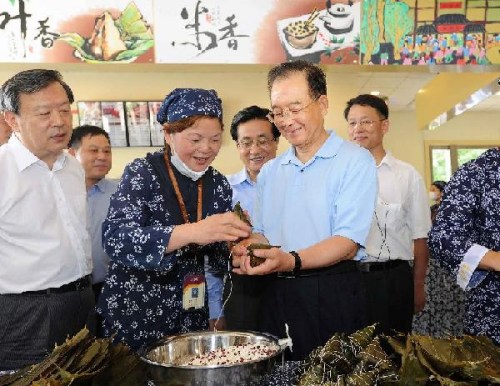 Chinese Premier Wen Jiabao (R front) wraps up zongzi, dumpling made of sticky rice and different fillings wrapped in bamboo or reed leaves, in Wufangzhai company in Jiaxing, east China's Zhejiang Province, Aug. 15, 2012. Wen made an inspection tour in Zhejiang on Tuesday and Wednesday. (Xinhua/Li Tao)