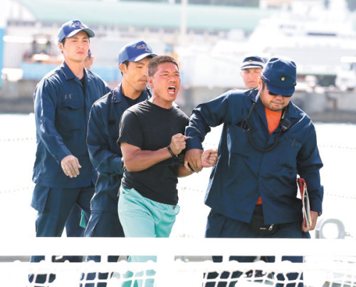 An activist who landed on the Diaoyu Islands is taken into police custody in Naha, the capital of Okinawa, on Thursday. JIJI PRESS / Agence France-Presse