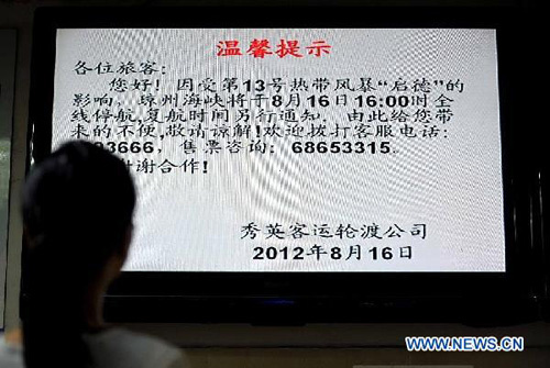 A passenger looks at shipping information at a port in Haikou, capital of south China's Hainan Province, Aug. 16, 2012. Local maritime safety administration decided to suspend shipping services across the Qiongzhou Strait on Thursday as typhoon Kai-Tak approaches. (Xinhua/Guo Cheng)