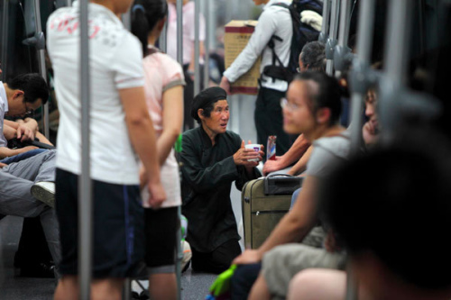 A woman begs on the subway in Shanghai in July. Gao Erqiang / China Daily